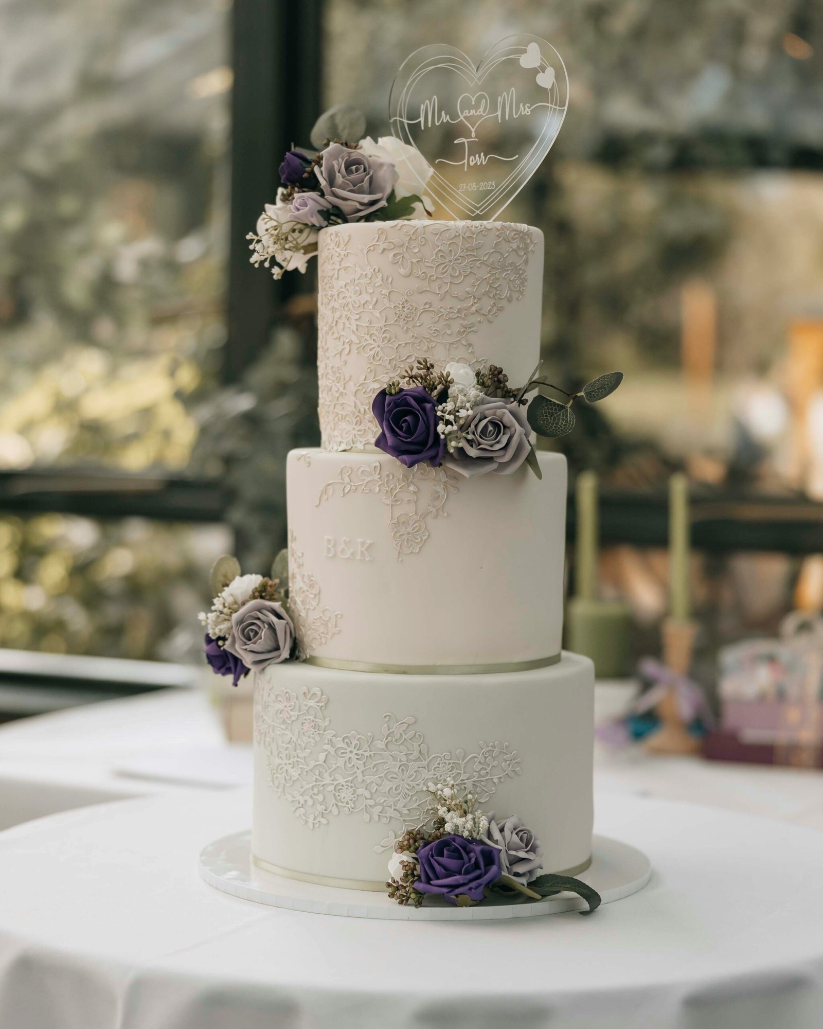 A three tiered wedding cake with purple flowers